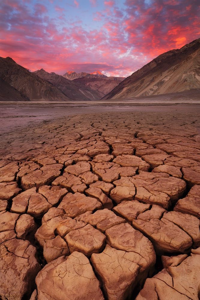 Paysage de terre craquelée avec montagnes au coucher du soleil
